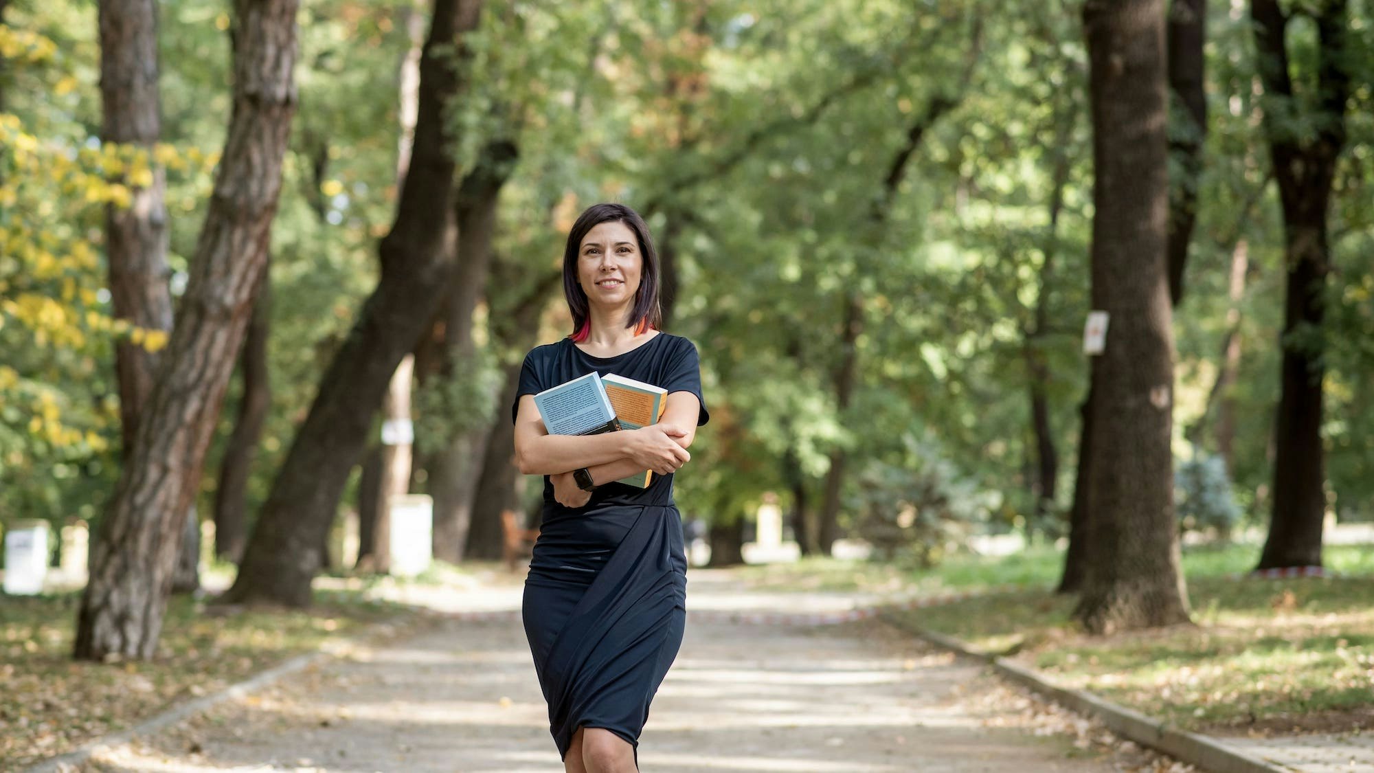 Woman in the park, holding books.