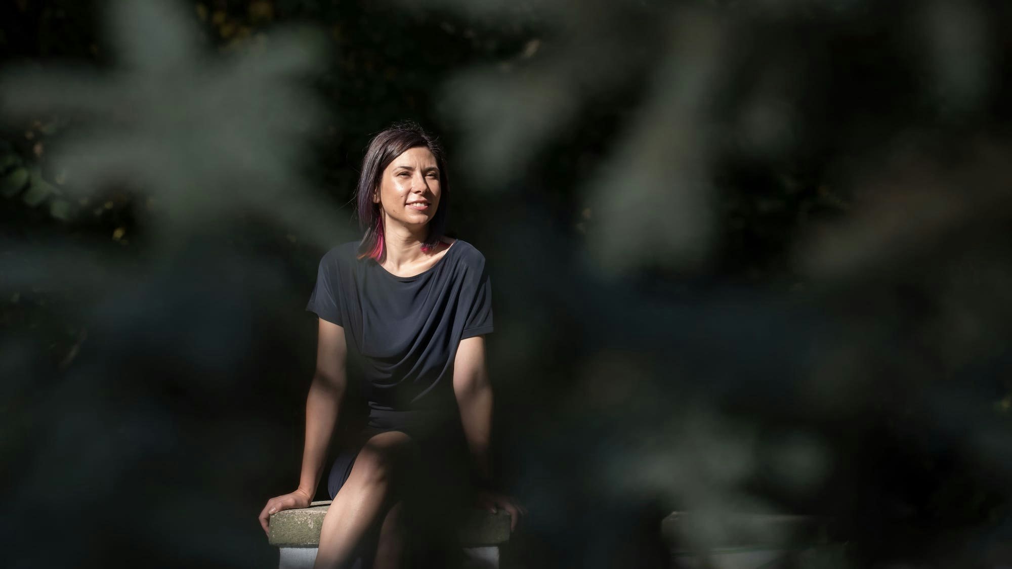 Woman sitting on a stone parapet.