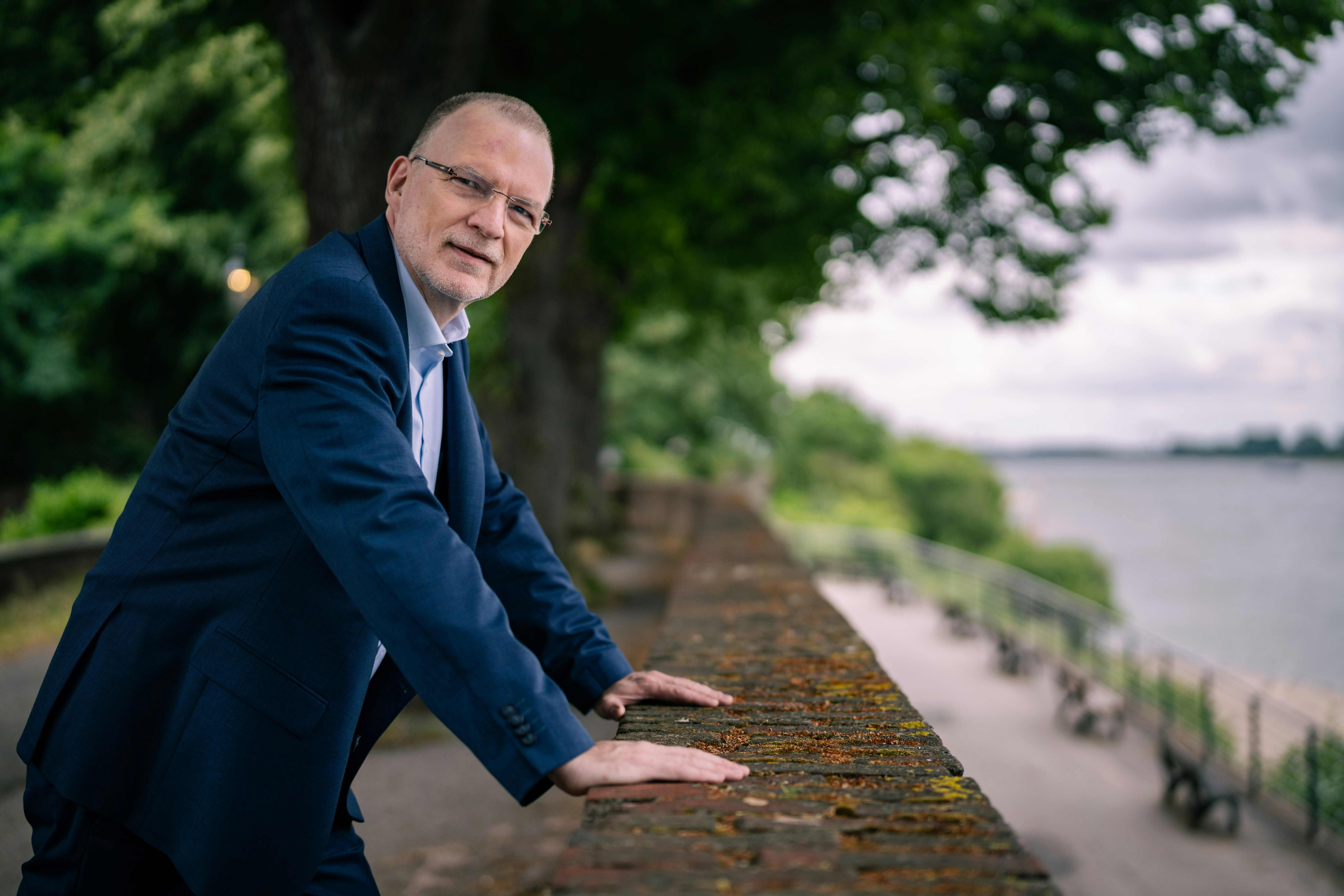 Matthias stands at a wall wearing a suit.