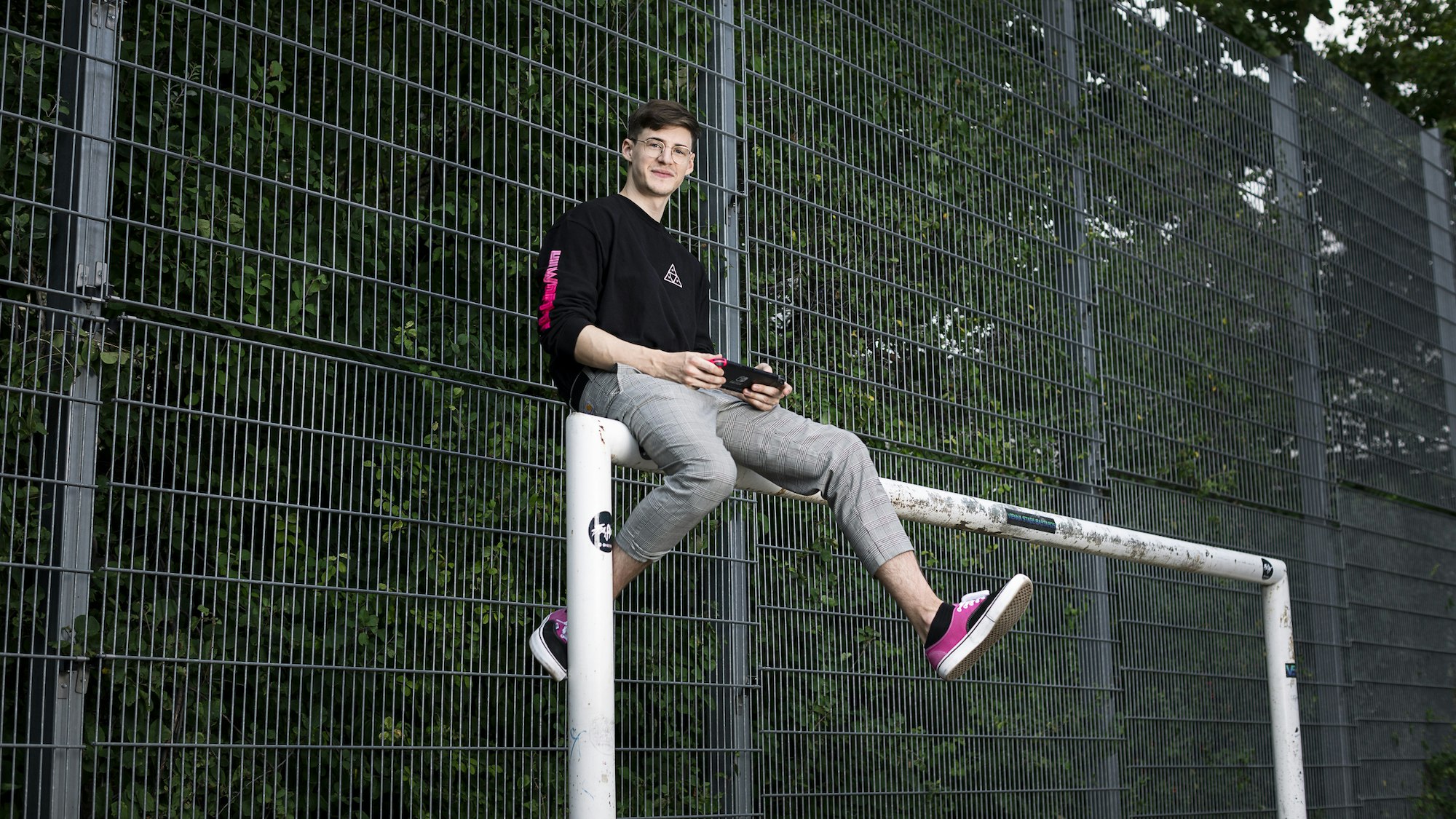Christoph is sitting on a soccer goal.