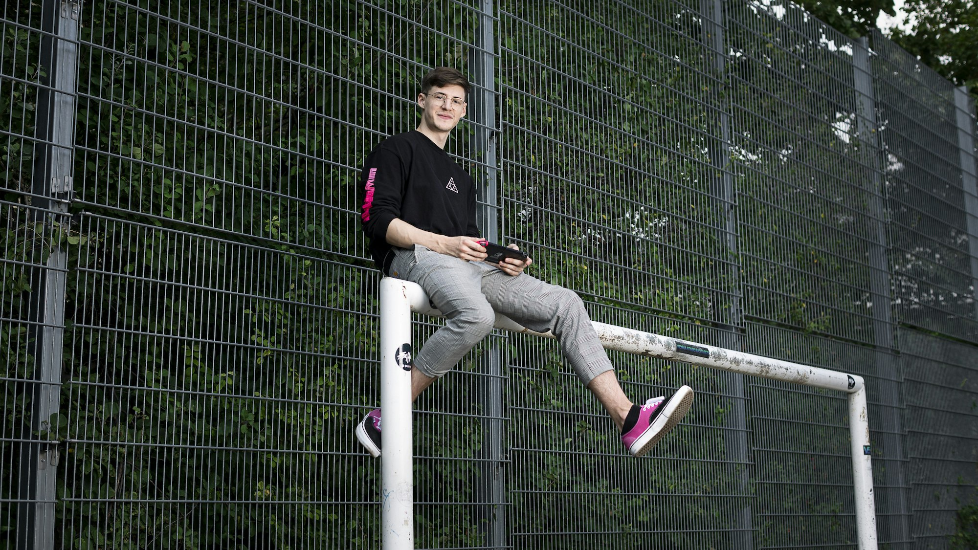 Christoph sitzt auf einem Fußballtor.