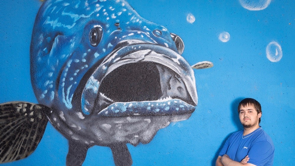 Franz is standing in front of a large street painting that shows a fish.