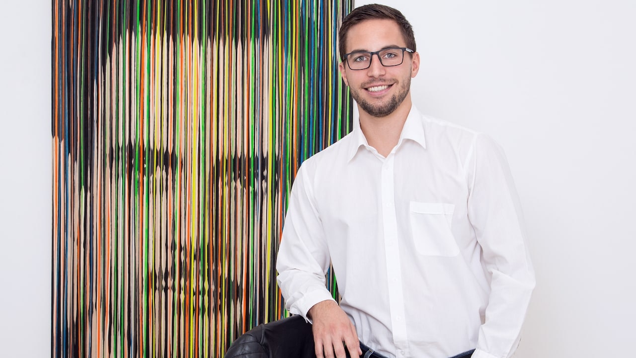 Peter stands in front of a colorful work of art in the office.