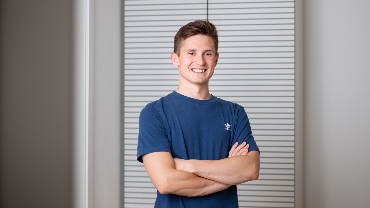 Christoph lächelt in die Kamera in einem blauen T-Shirt.