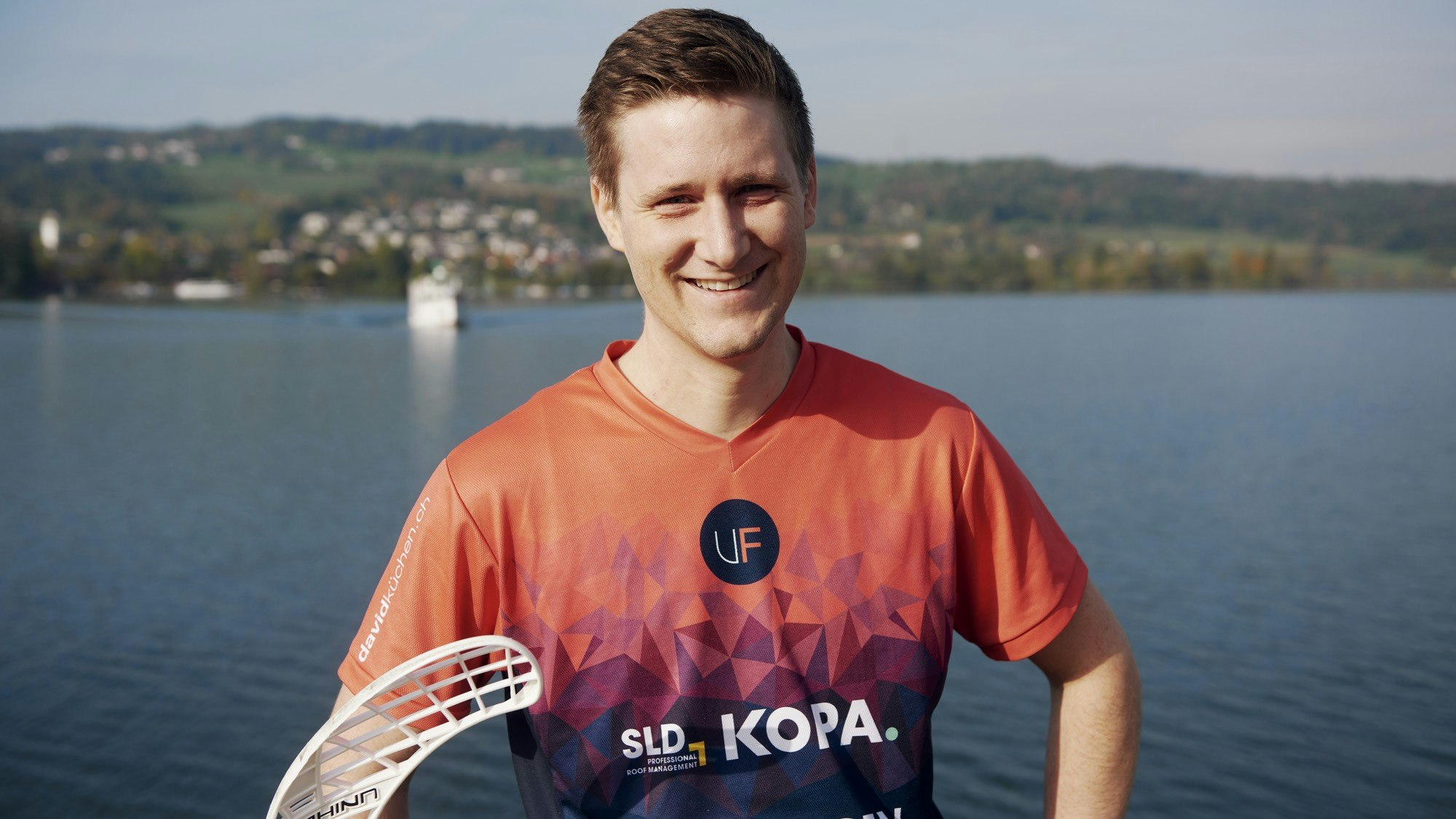 Man in sports outfit with lake in the background.