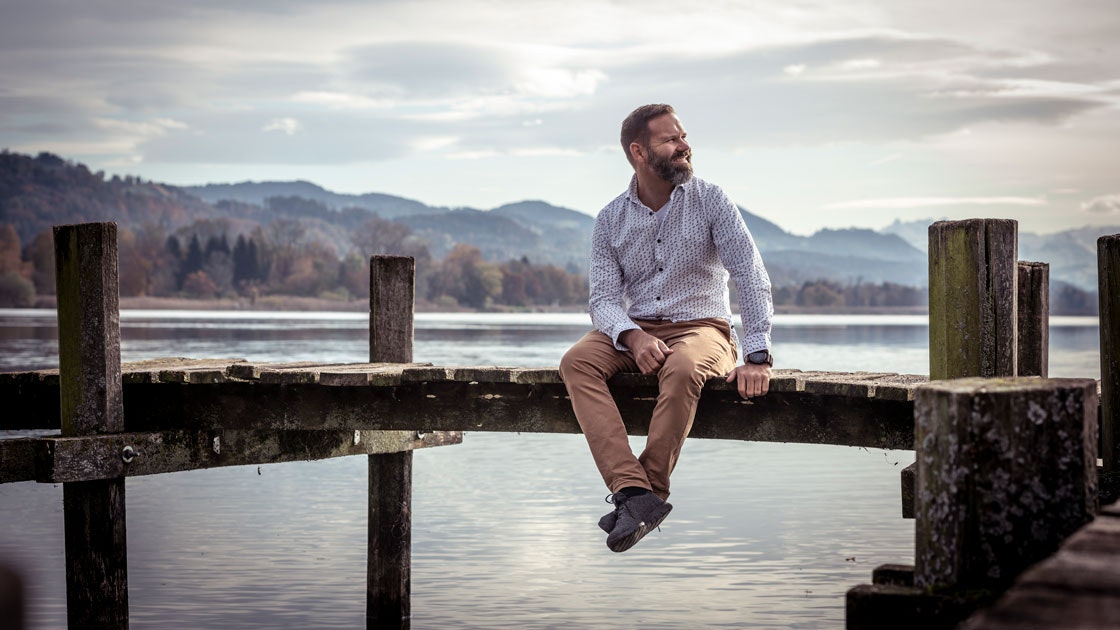 A man sits on a pier and looks into the distance.