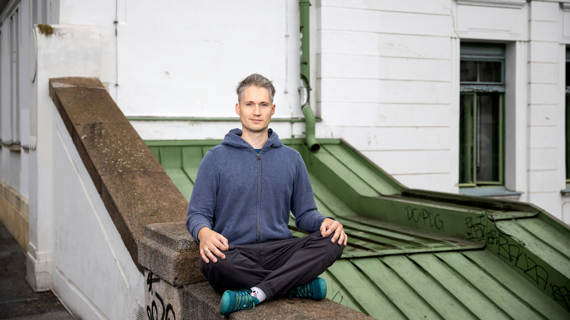 Martin sits cross-legged on a wall.