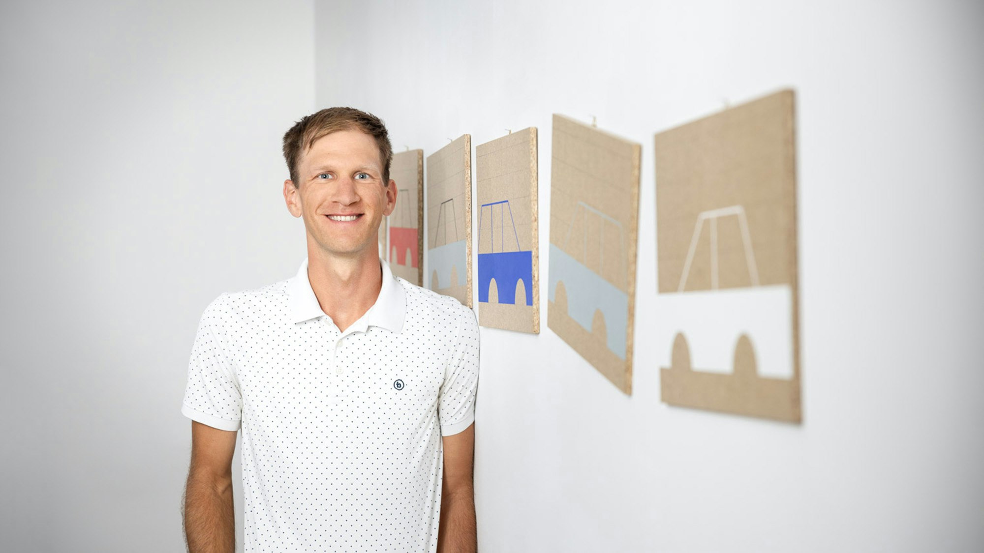 Lukas is standing in front of a work of art in the office.