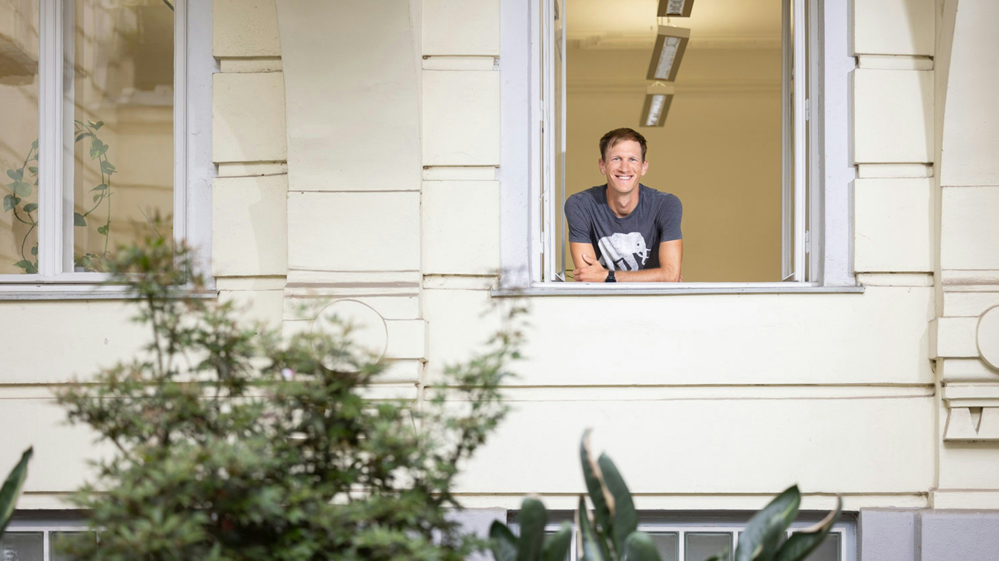 Lukas steht vor den offenen Bürofenster.