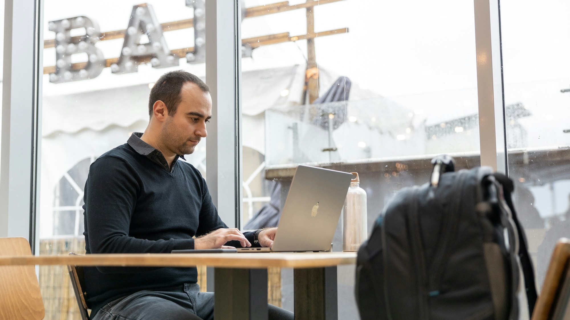 A man in a black shirt working on a laptop
