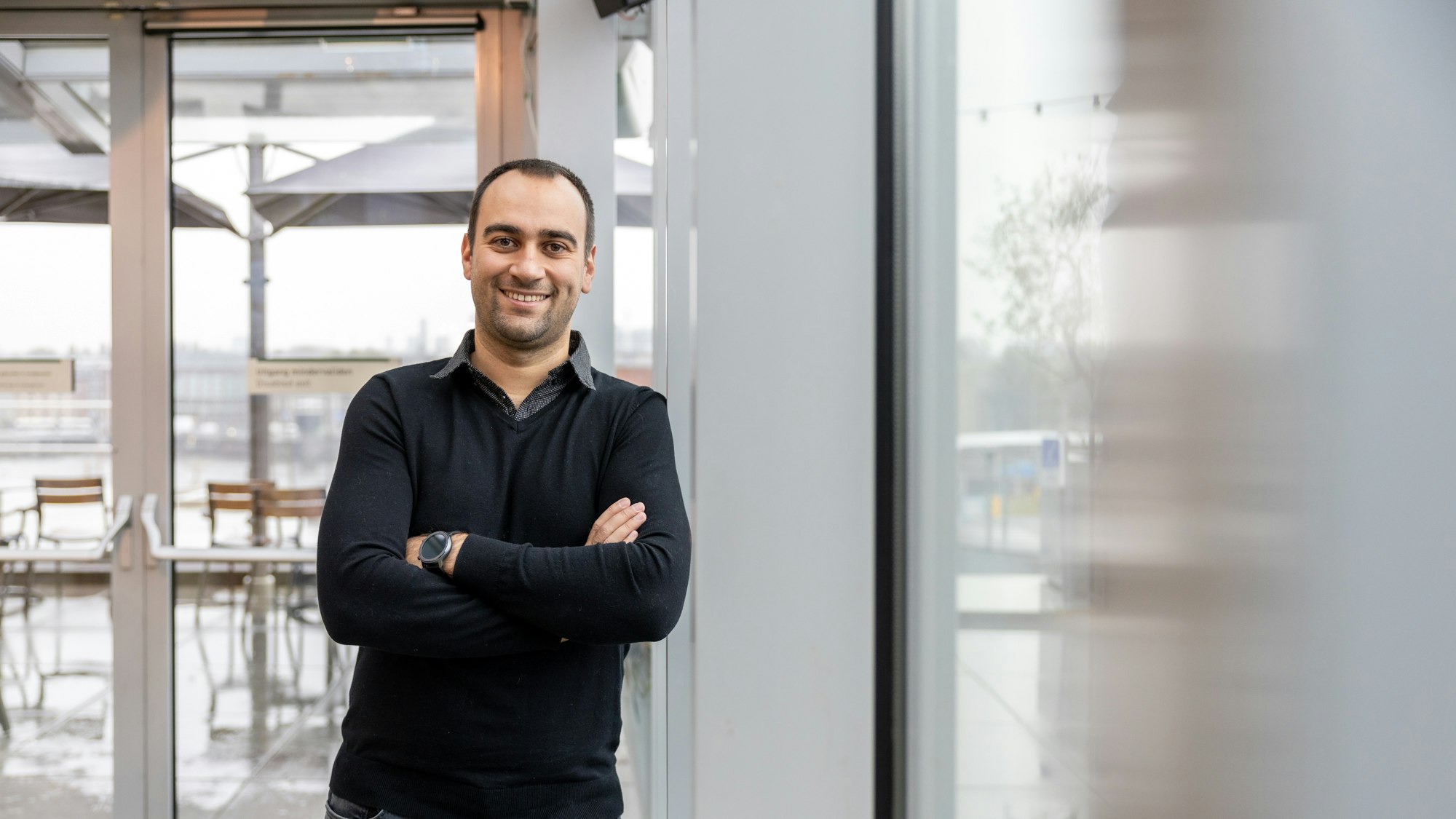 A man in a black shirt leaning against a window