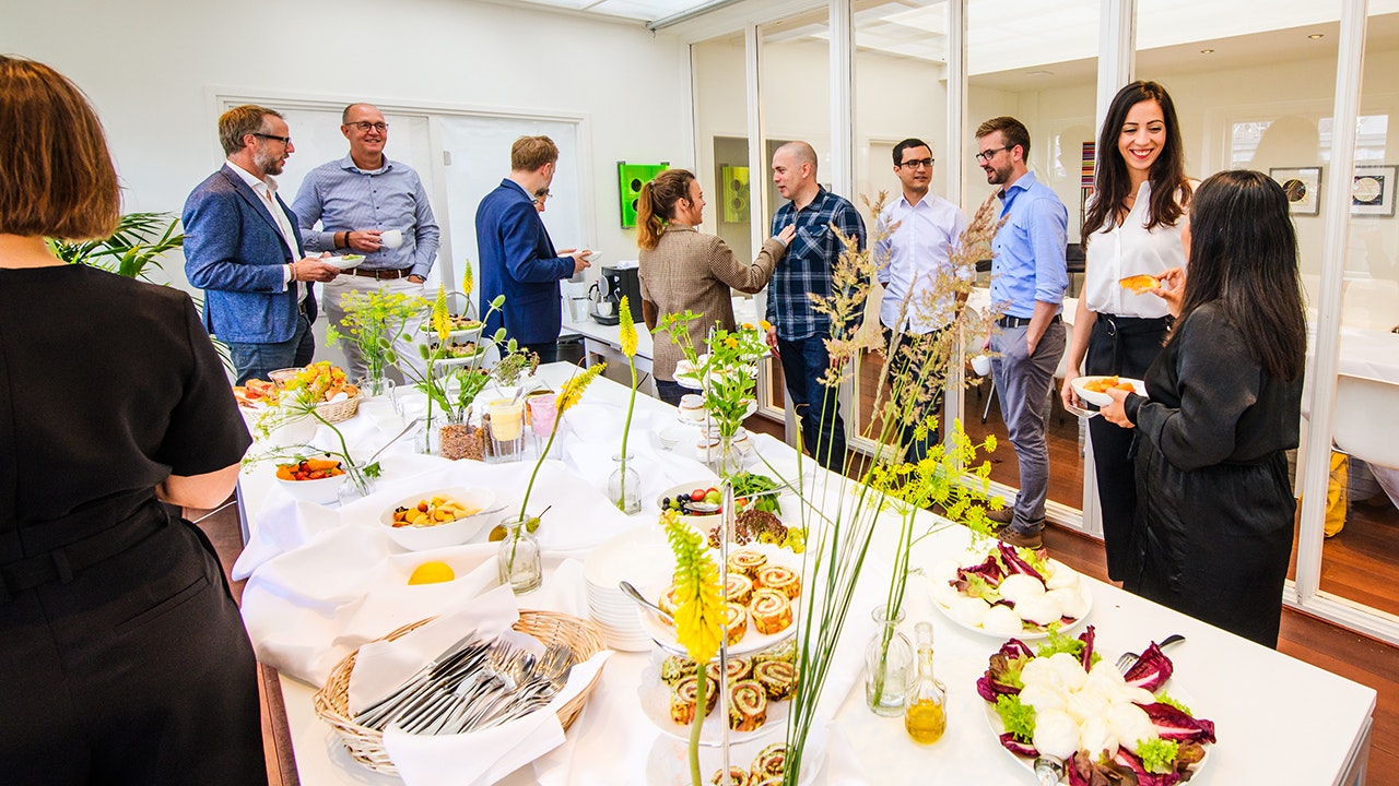 Menschen stehen um ein Buffet herum und unterhalten sich