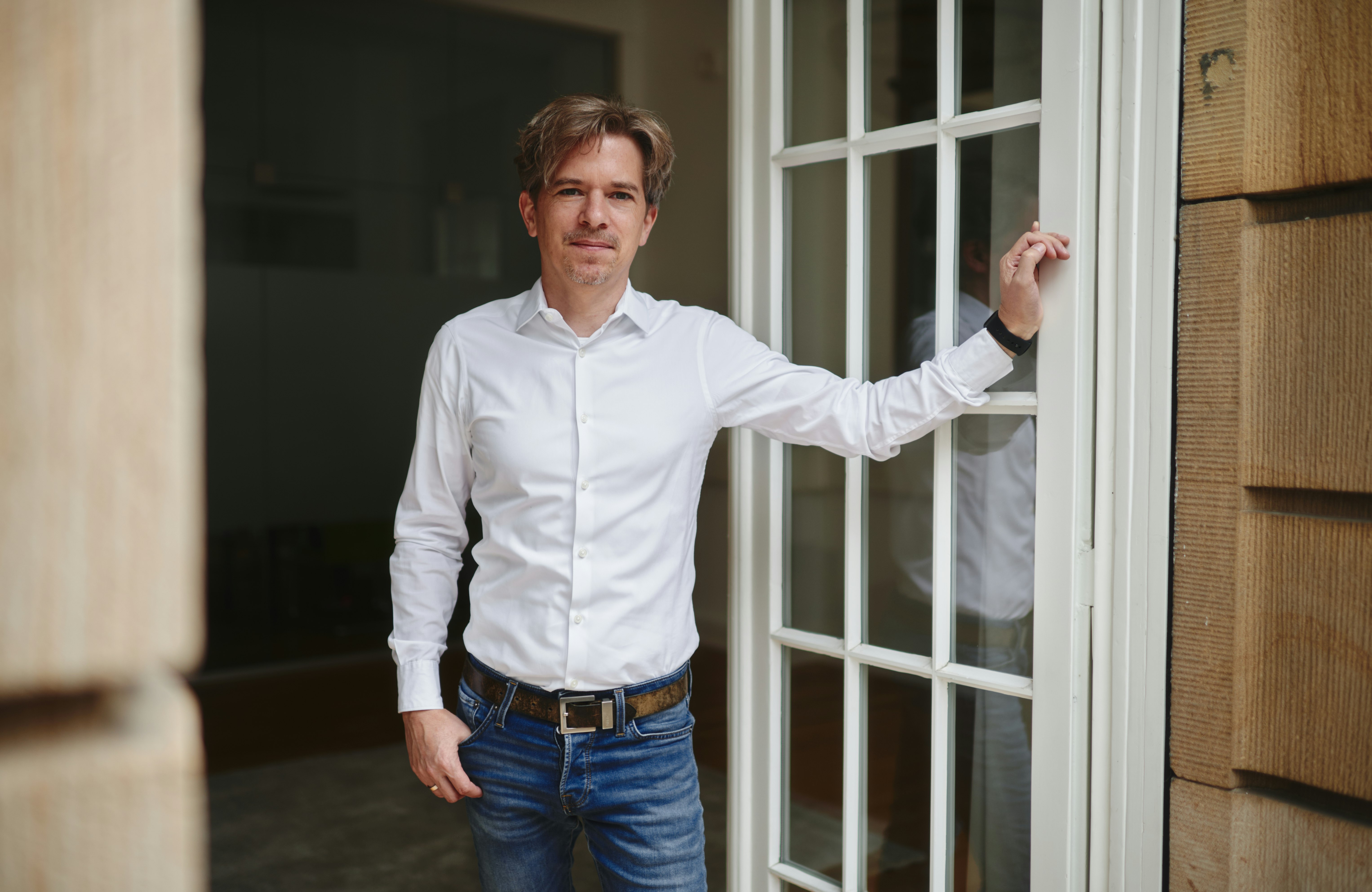 Christian Schröther blickt aus einer Balkontür ins Freie.