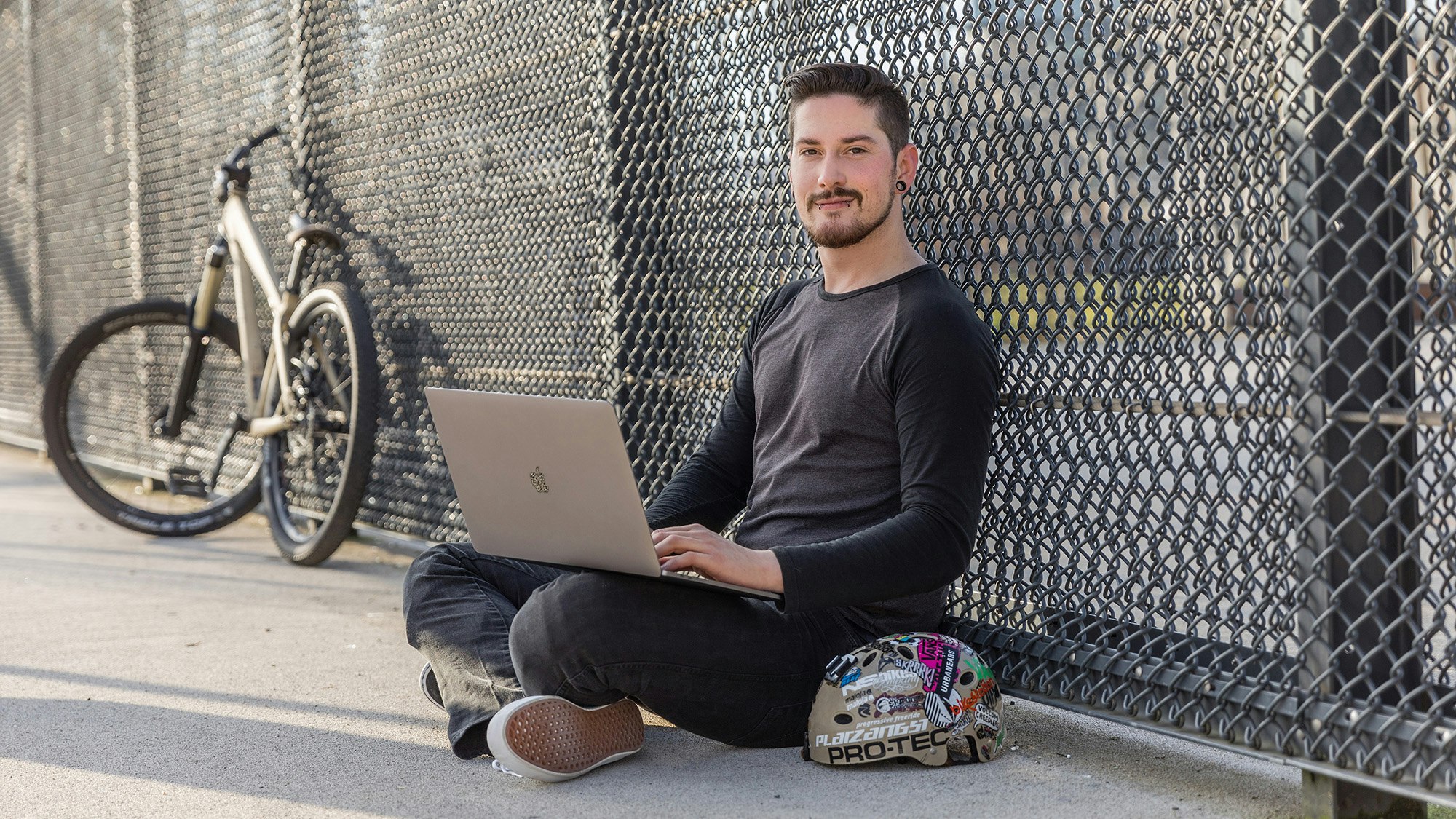 Daniel sitzt mit Rechner und Bike im Skatepark