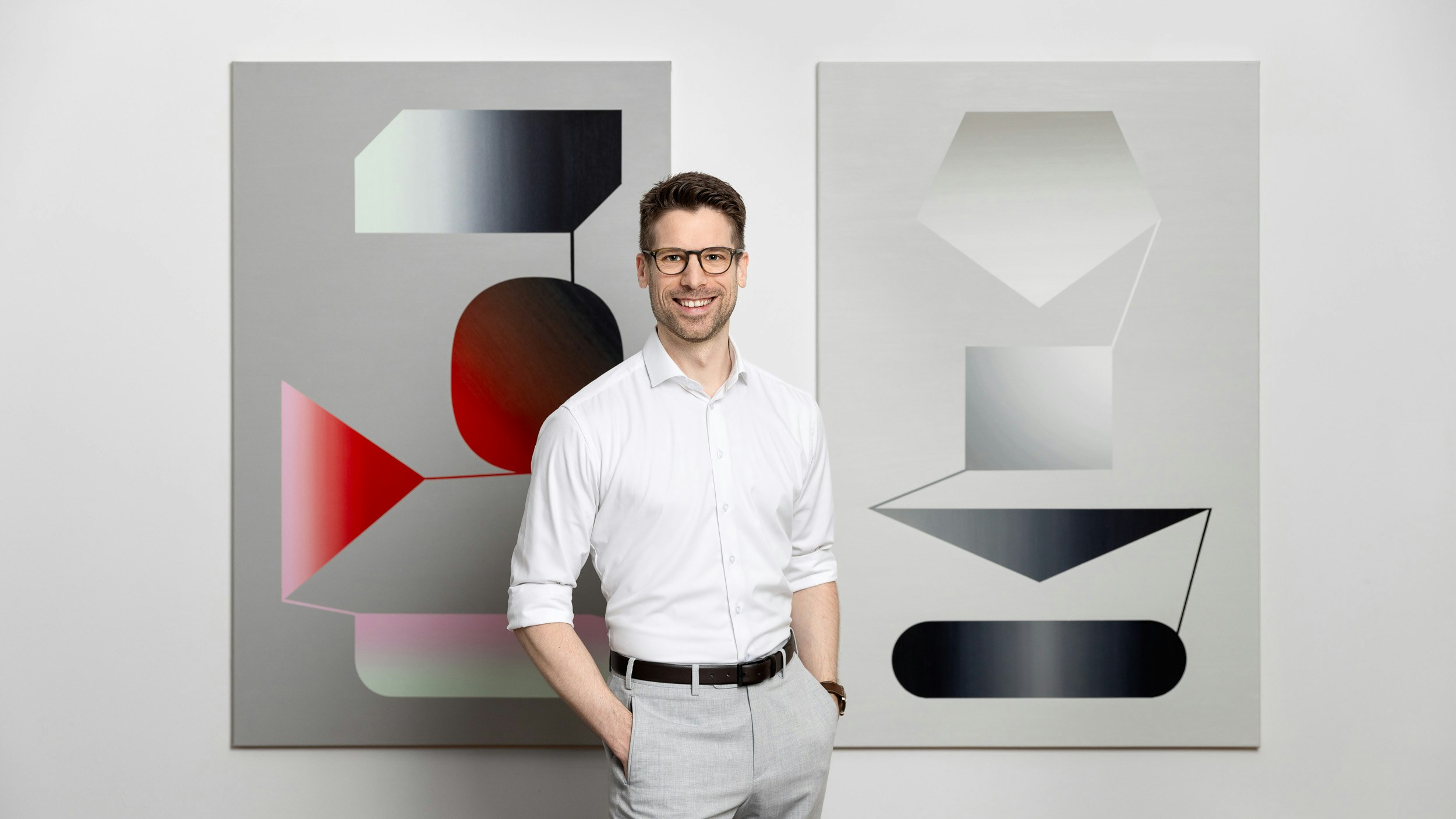 Im Hintergrund hängen Kunstwerke an der Wand.