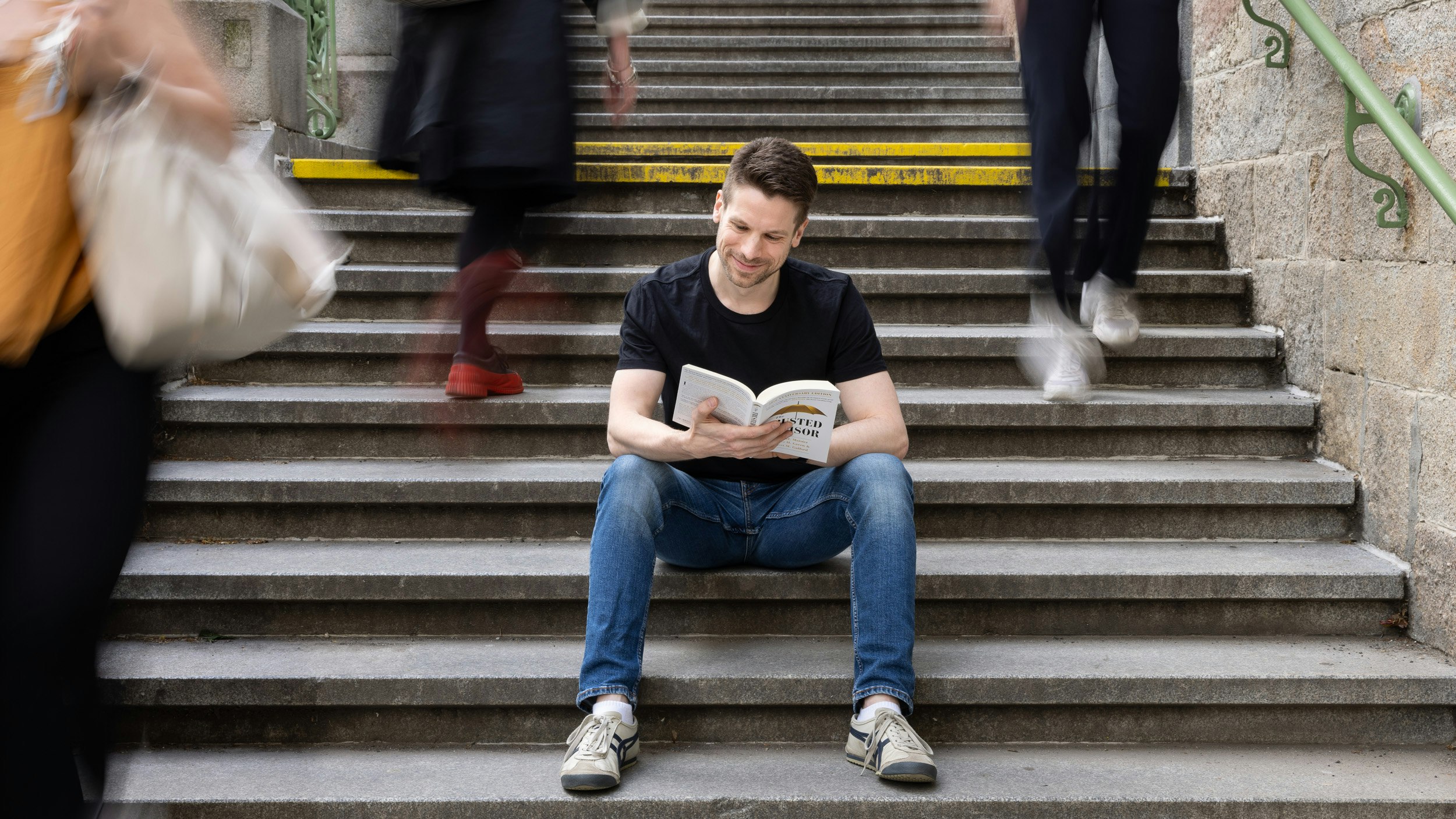 Er liest ein Buch auf einer Treppe.