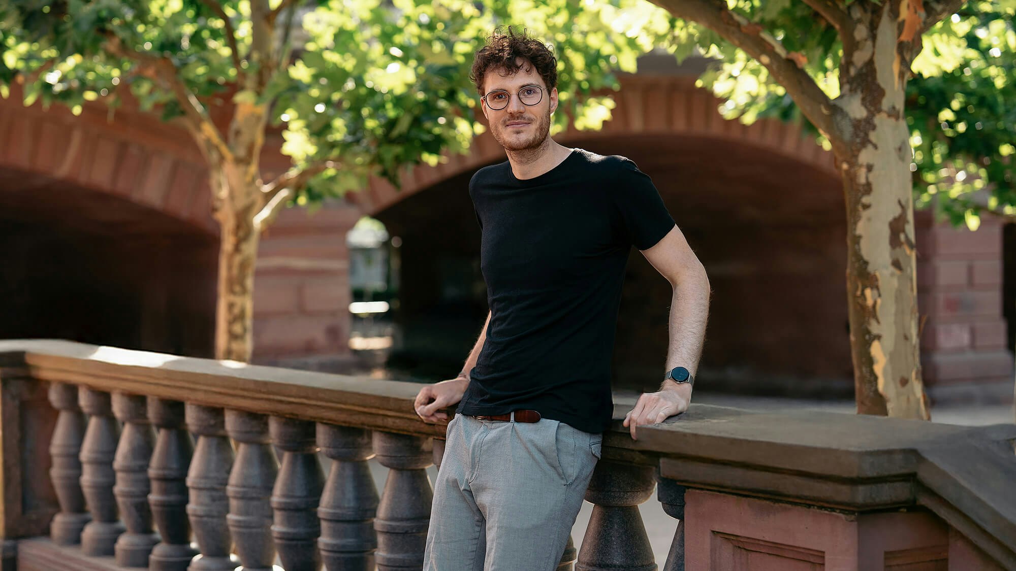 Philip Wintersteiner steht draußen und lehnt an einem steinernen Geländer.