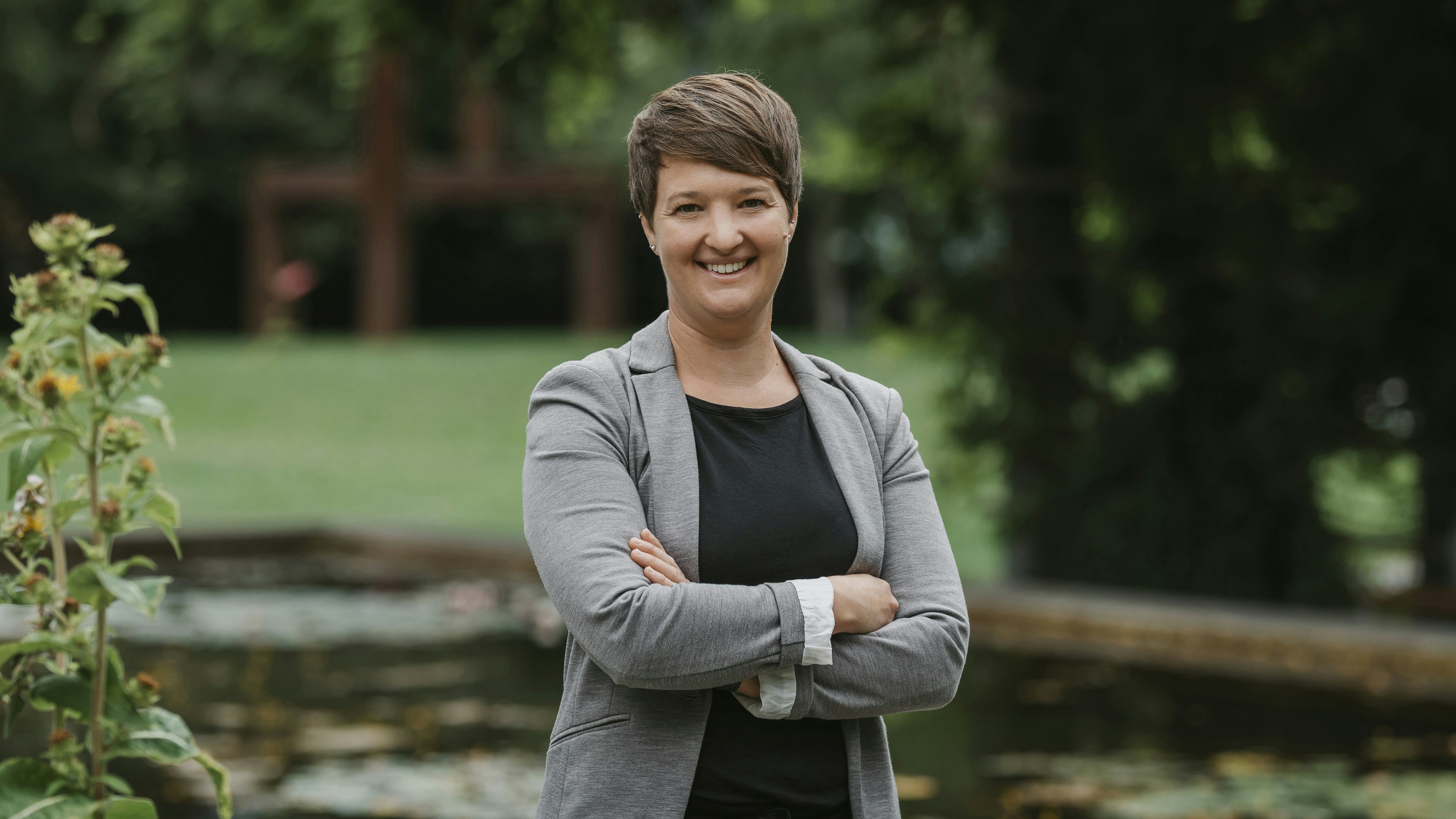Iris Stroebele steht vor einem Teich mit Rasen im Hintergrund