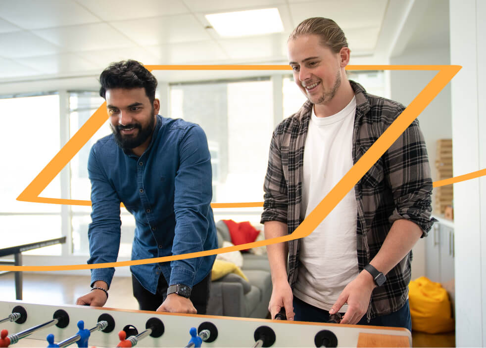 Two men in casual clothes playing table football