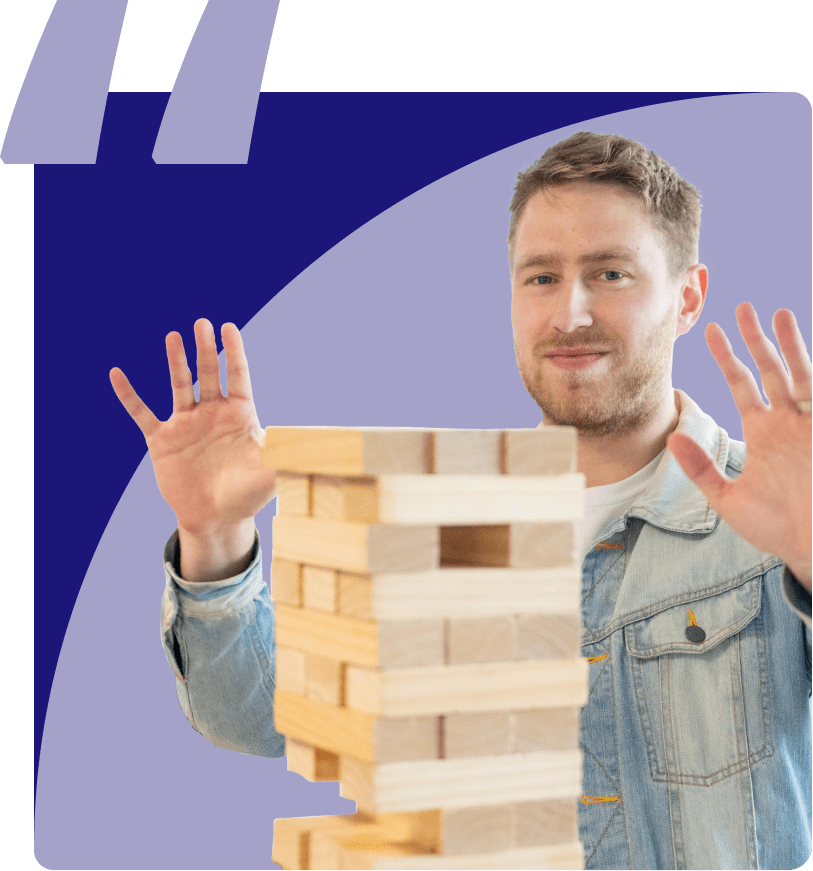 A man standing behind a tower of jenga blocks