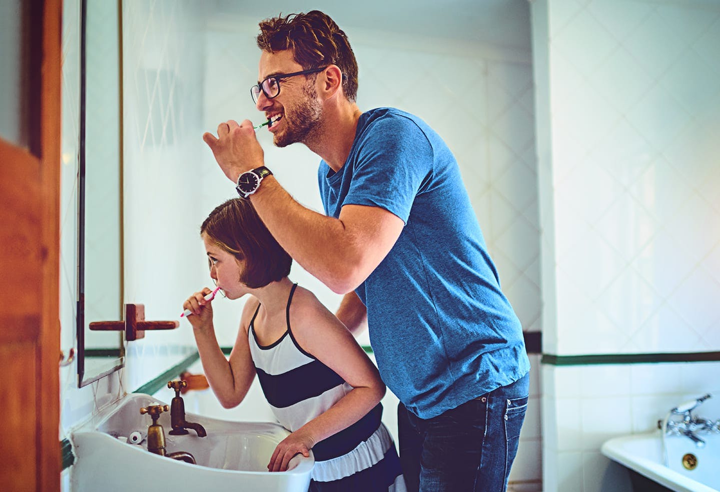 Man and daughter brushing their teeth