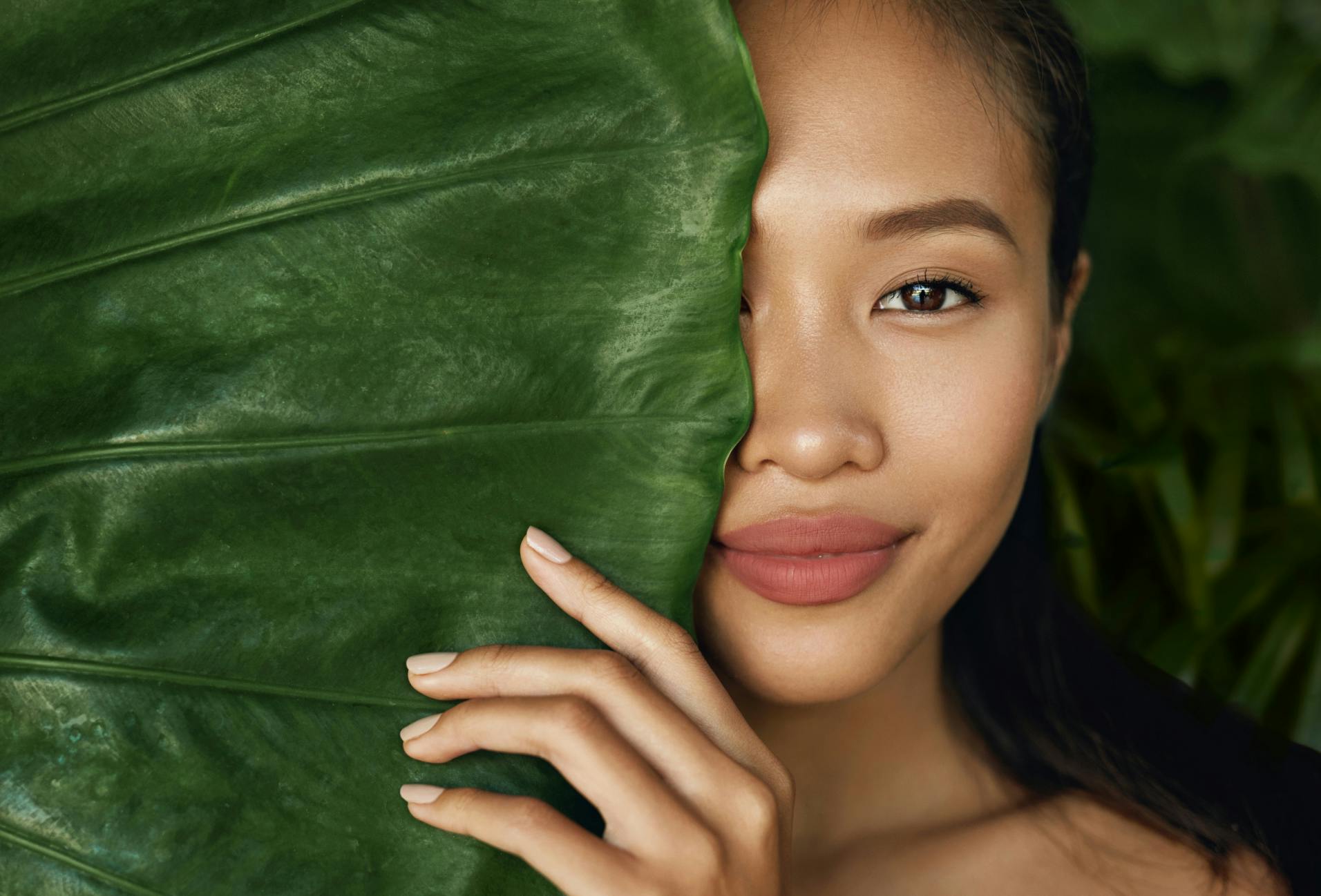 woman standing behind a big leaf