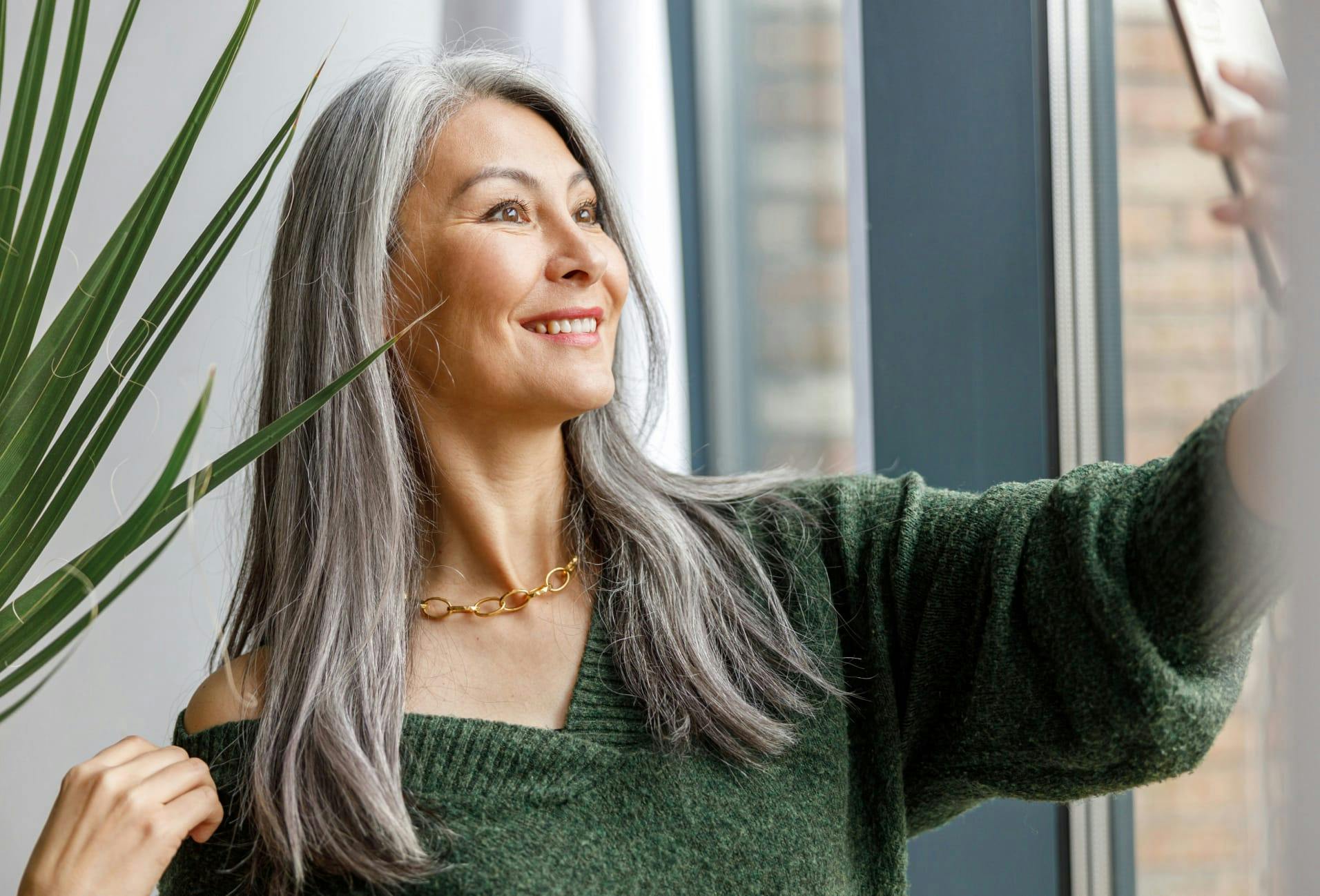 woman with long grey hair wearing a green sweater