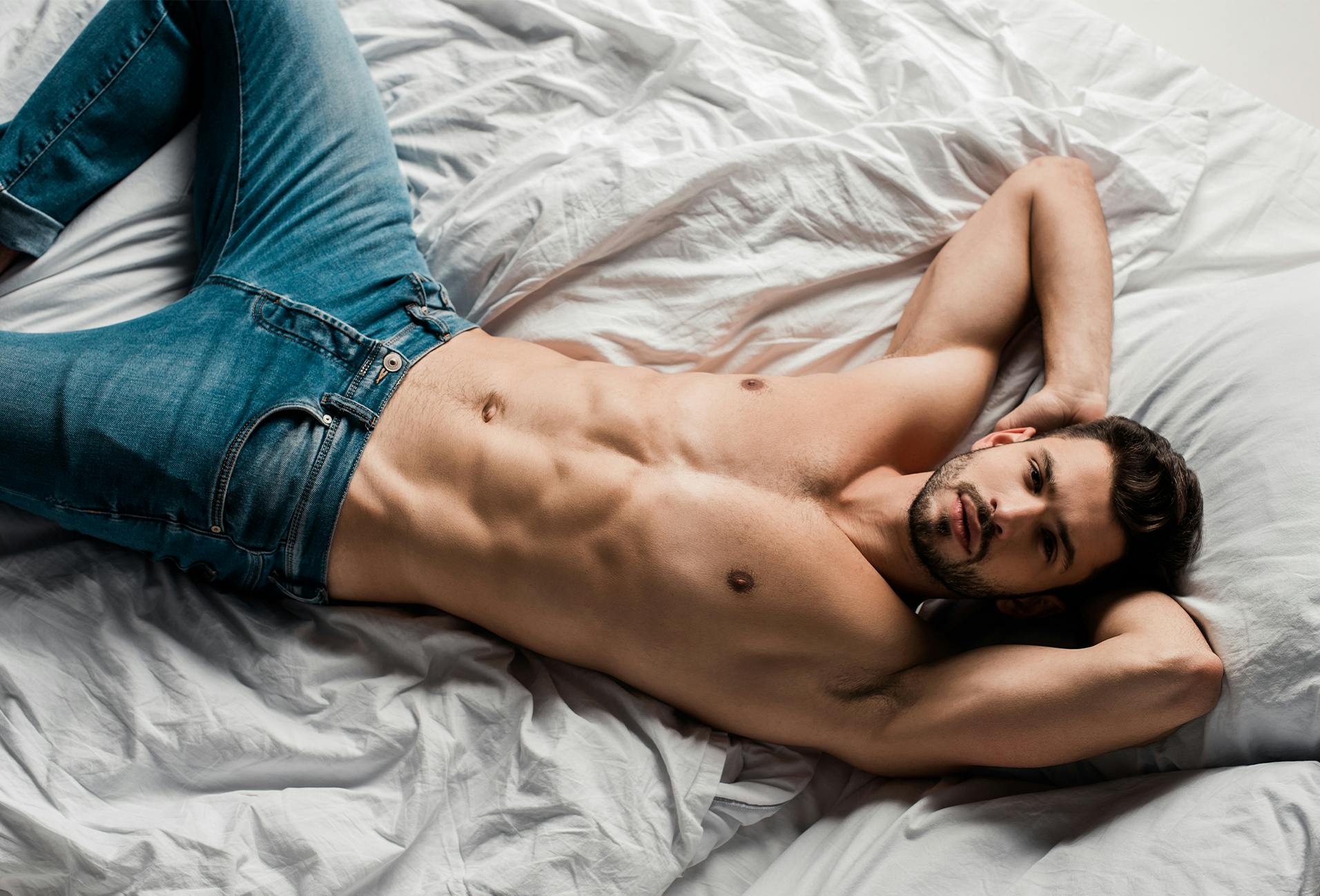 man laying in bed in jeans and no shirt