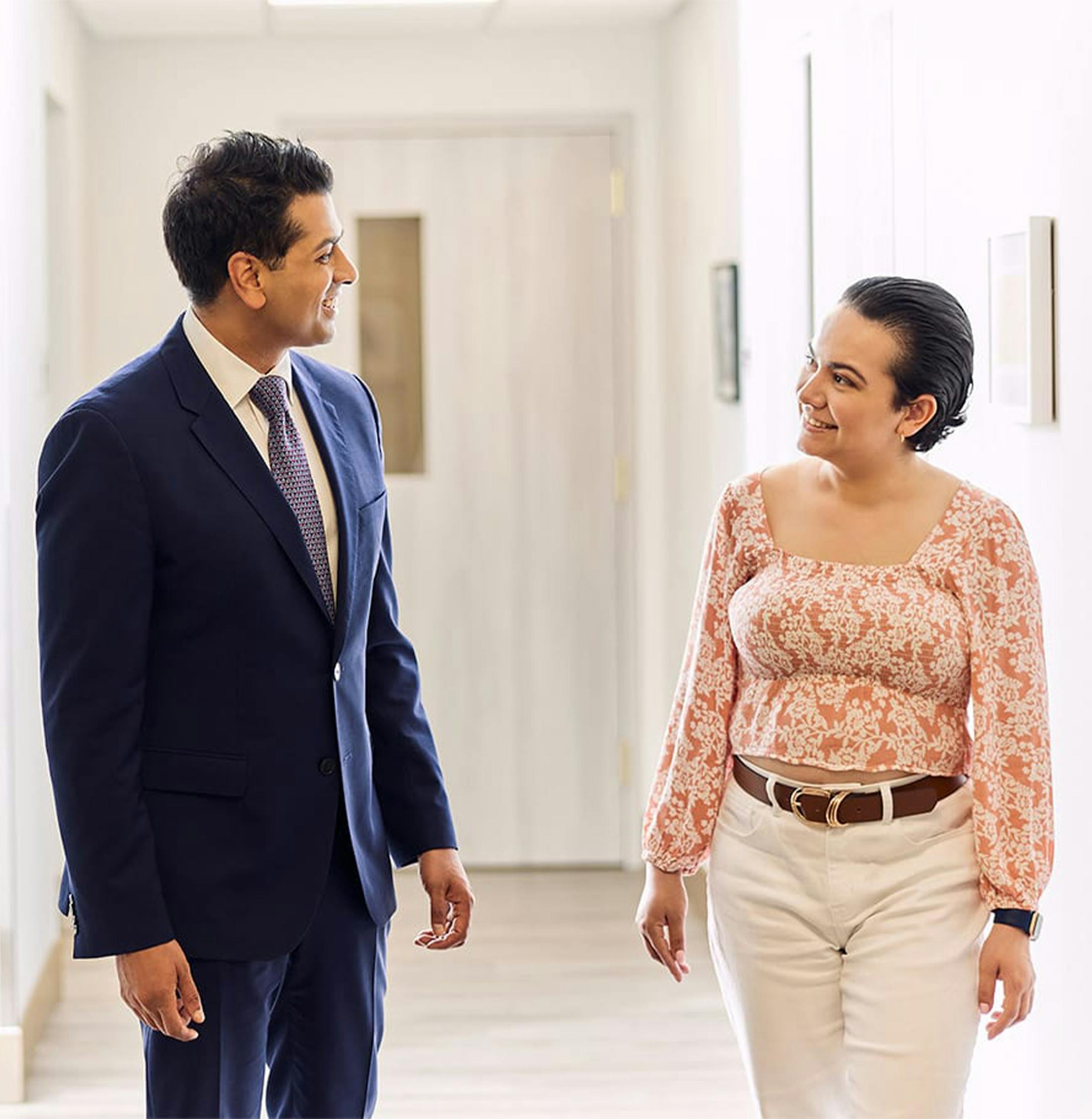 two people standing in a hallway talking to each other