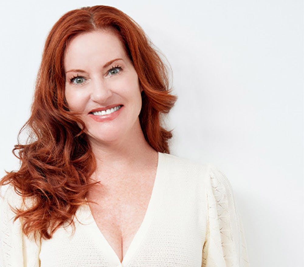 smiling woman with red hair and white sweater posing for a picture