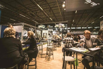 people seated inside a trade show with tables and chairs