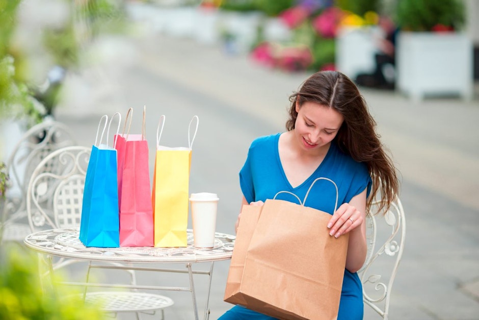Fashion happy girl with bags after shopping drinking coffee in openair cafe