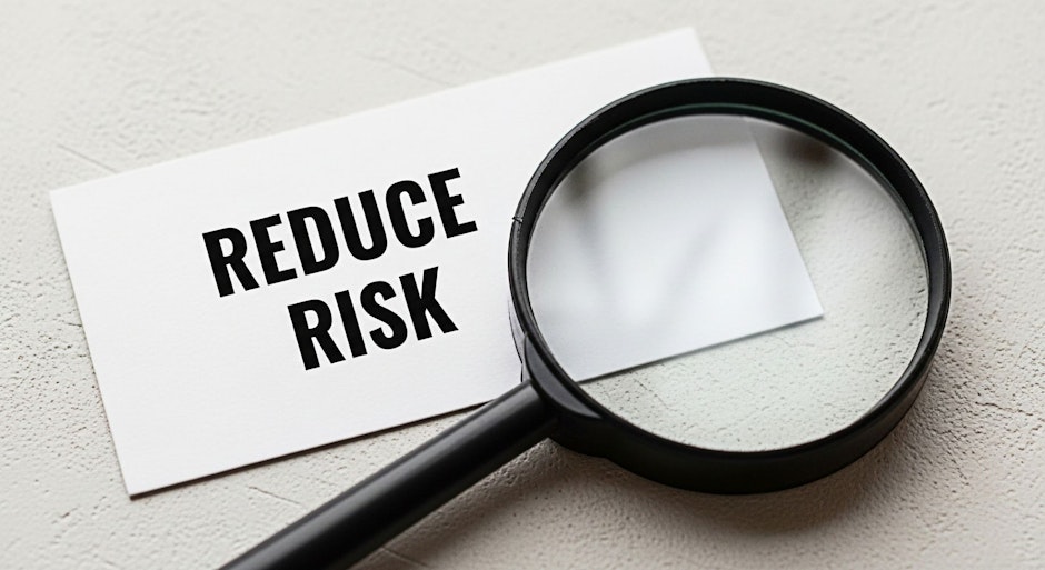 Magnifying glass focusing on a card with the words Reduce Risk