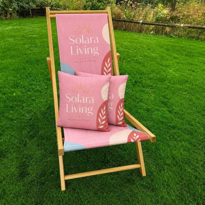 Custom printed pink branded cushion displayed on a matching personalised deckchair outdoors