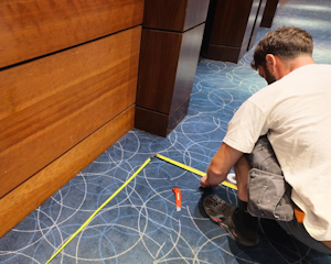 Man leant down, measuring lengths of a floor.
