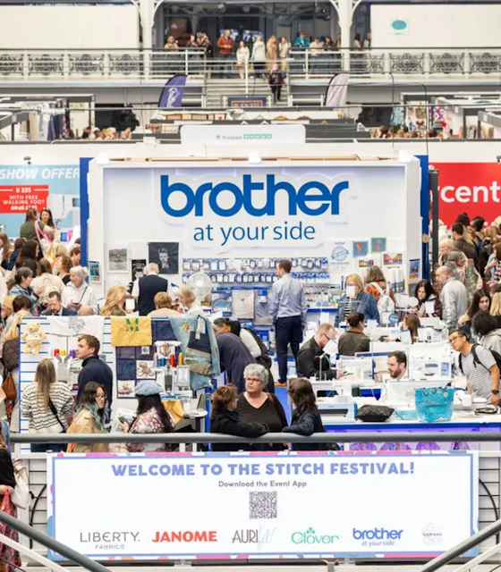 A large and busy exhibition hall with a banner welcoming its attendees.