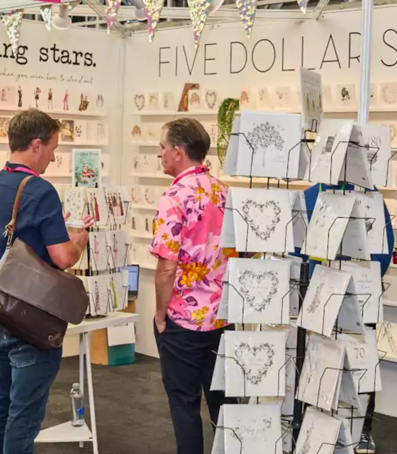 Two men standing next to a rack of card with hearts designed on them.