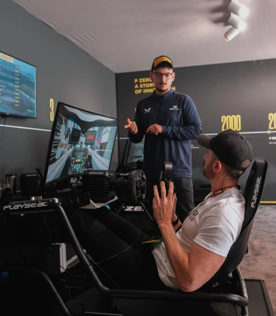 A Man sat on a racing chair playing a simulation of an F1 Racer.