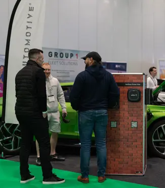 Two men stood in front of an Evo charging station within an exhibition.