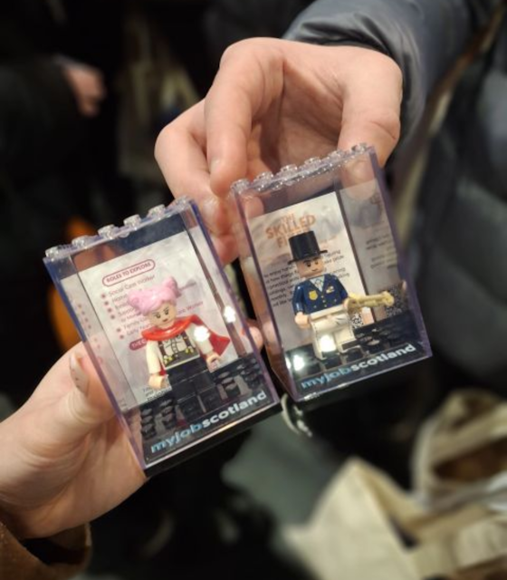 Two small boxes of lego minifigures held up.