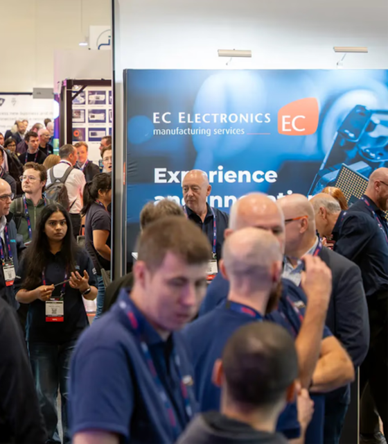 An exhibition hall of uniformed men in blue polos and lanyards standing next to another.