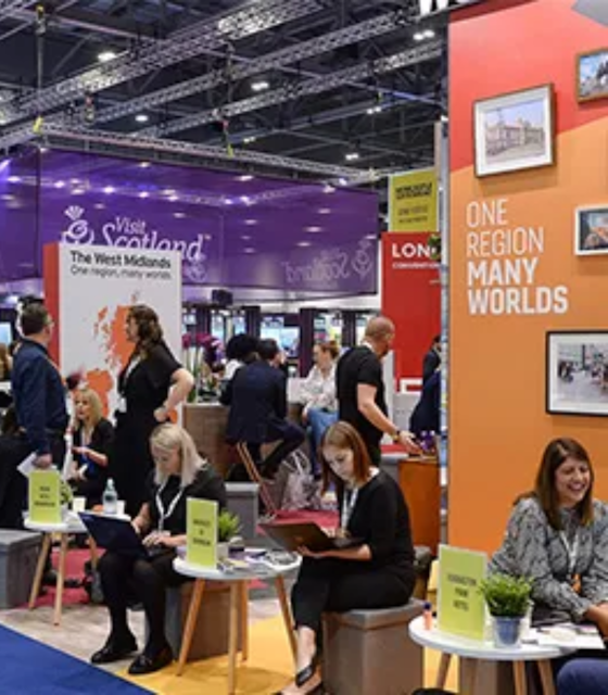 People sat down ,on laptops, at circular desks at an exhibition.