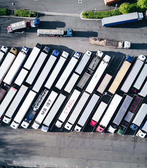 A row of Trucks lined up and parked from an aerial perspective. Photo by Nigel Tadyanehondo on Unsplash