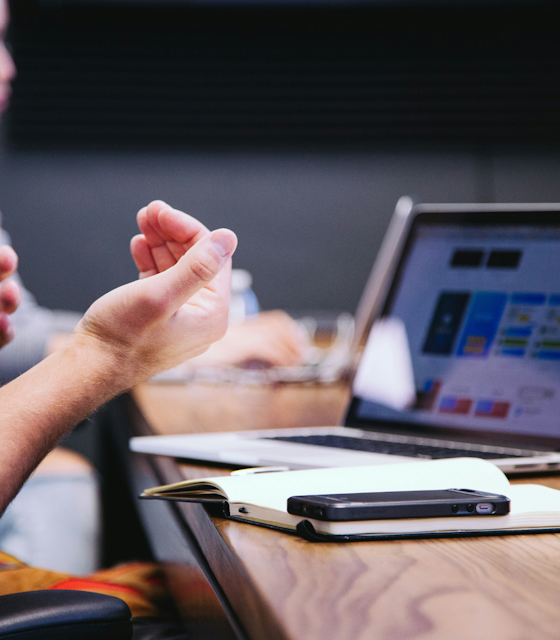 A set of hands at a business meetings next to a laptop. Photo by Headway on Unsplash
