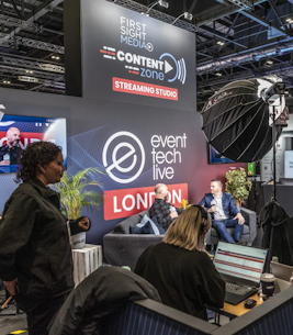 Behind the scenes of a podcast, two men sit on a sofa in the background while two women overlook at the Event Tech Live.