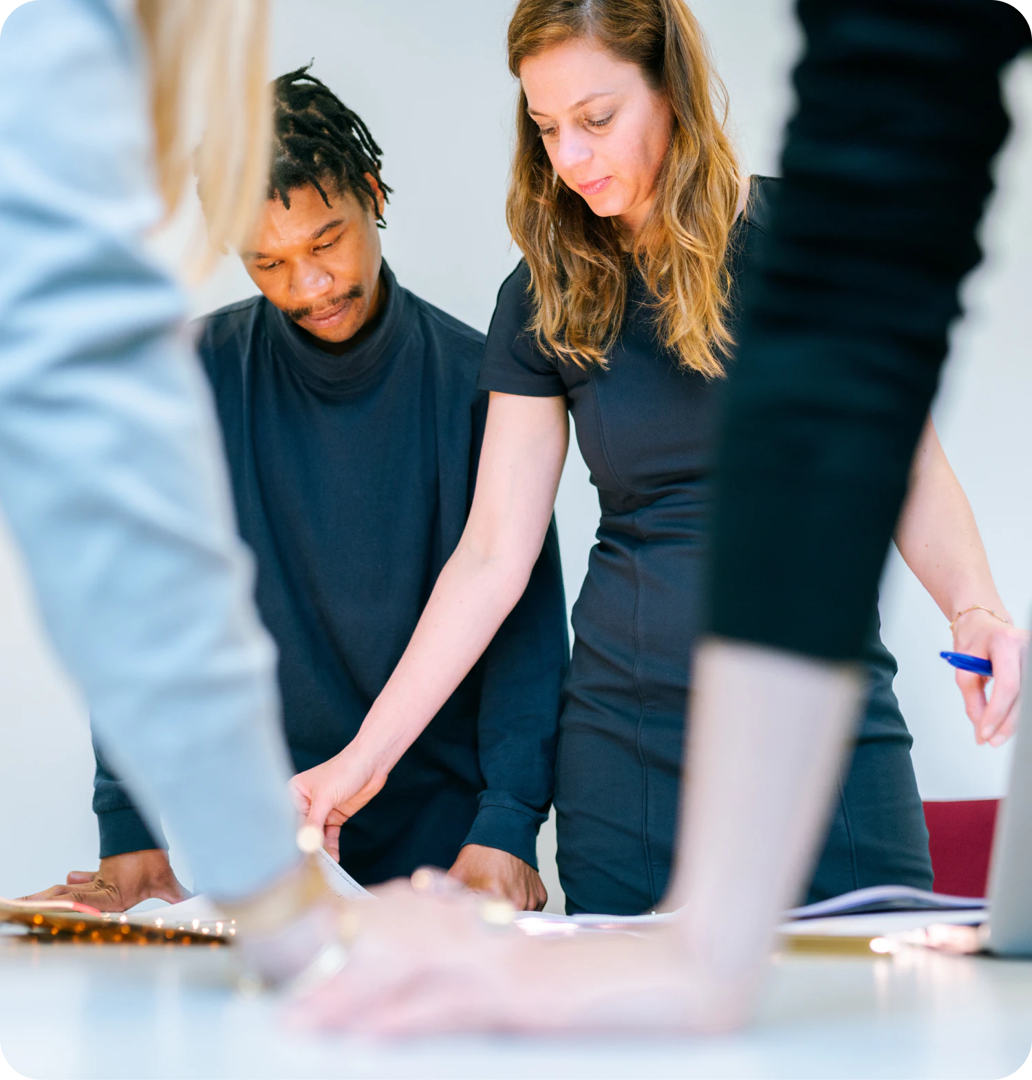 En grupp studenter står runt ett bord och tittar på papper