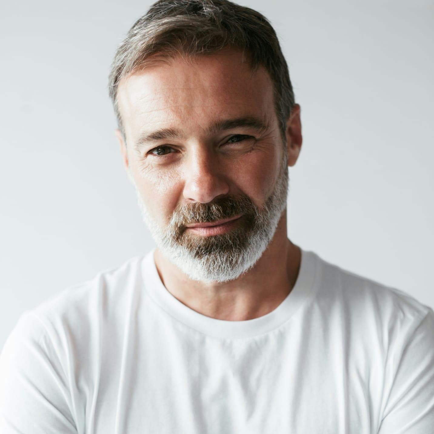 Man with grey beard and a white shirt.
