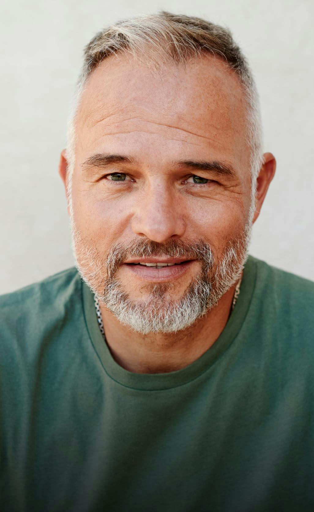 Dignified man with grey beard smiling.