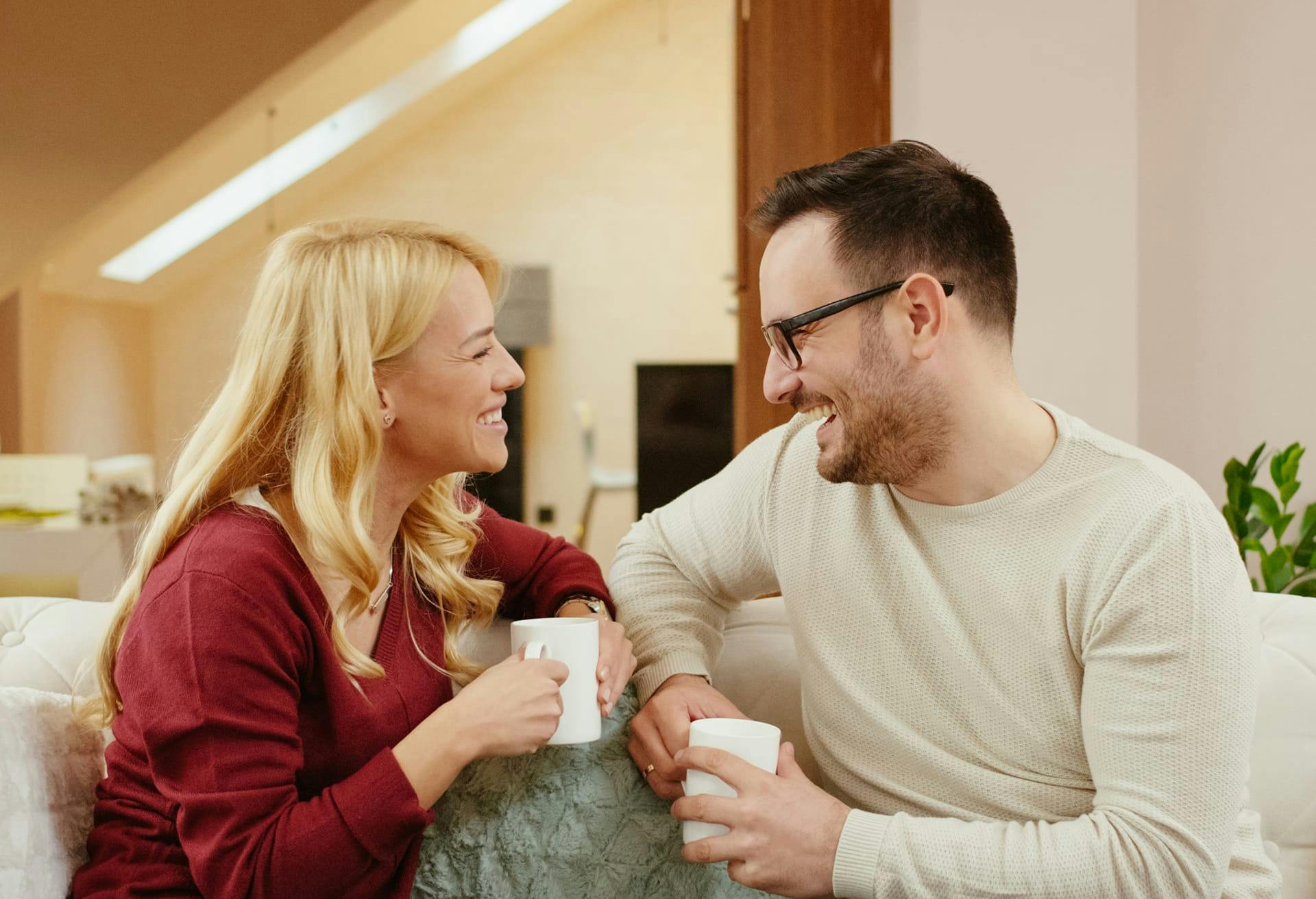 Man and woman sharing coffee together on a couch