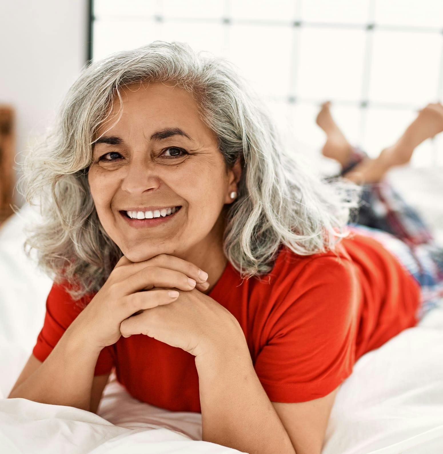 Woman laying on her stomach on a bed, smiling